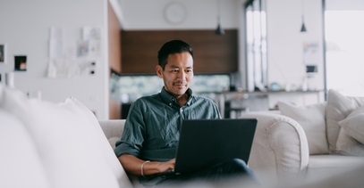 man sitting on couch looking at laptop